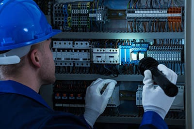 Electrician inspecting faulty electrical cabinet