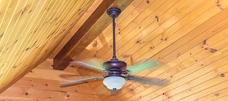 Ceiling fan installed on wooden beam spinning