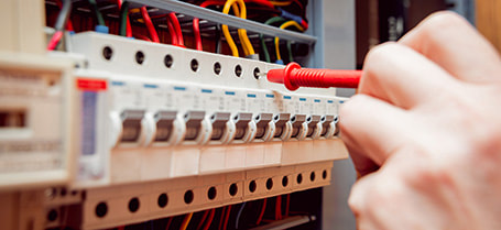 Electrician using voltmeter to detect a fault with an electrical switchboard