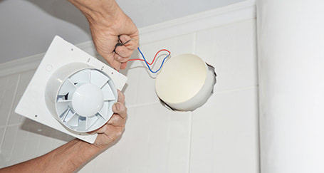 Exhaust fan being installed in a bathroom