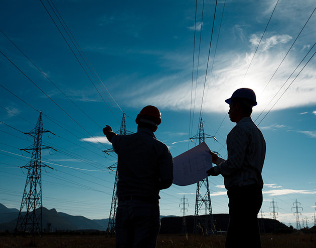 Grade A electricians in a field looking at electricity transmission towers